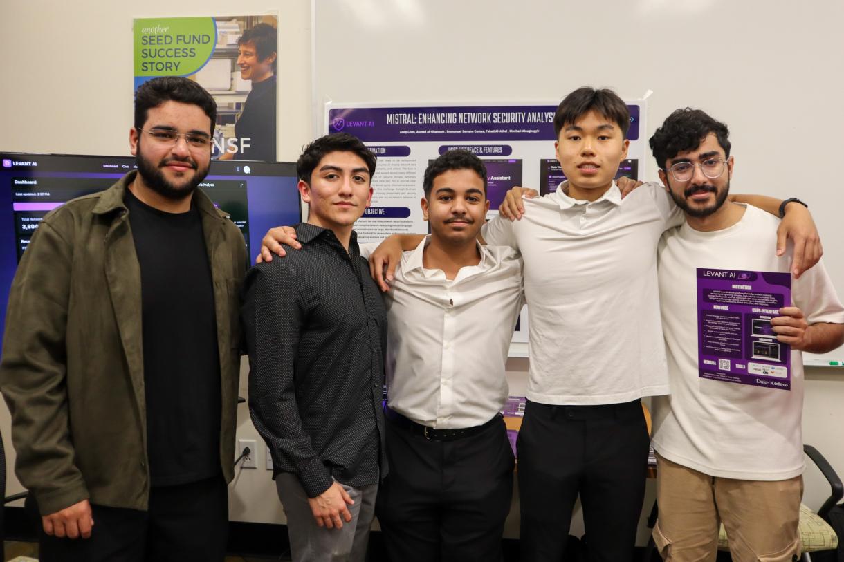 Five Code+ students together with their arms around one another in front of their project poster.
