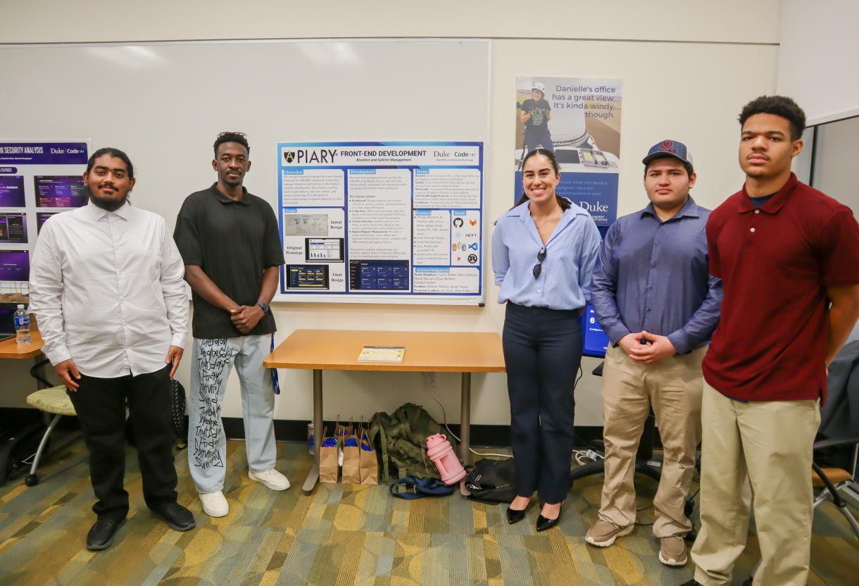 Five Code+ students stand in front of their project poster