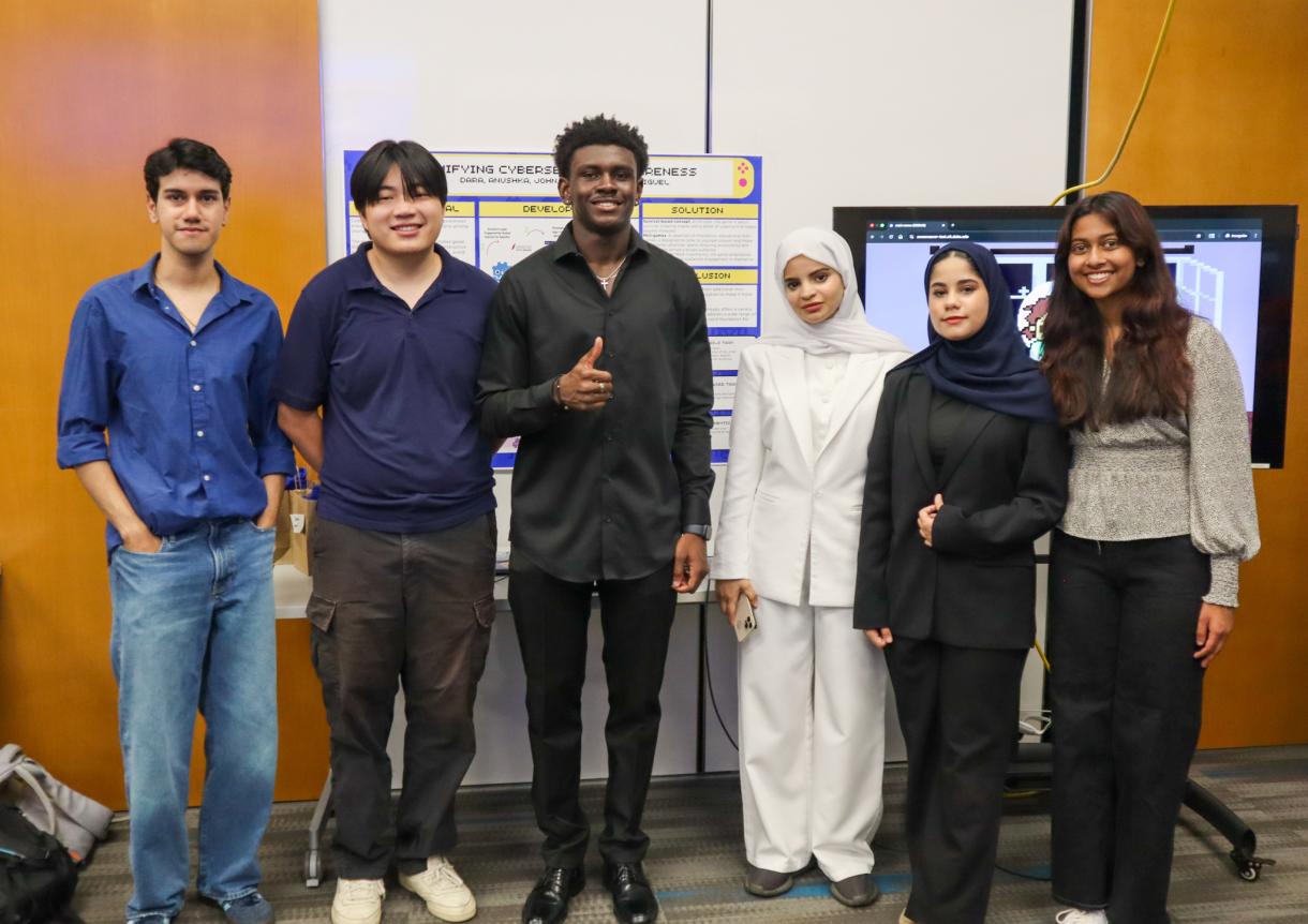A group of six Code+ students stand together in front of their project poster